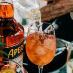 Aperol Spritz servido en vaso con botella de Aperol visible, estrategia de Campari para competir con la cerveza en eventos
