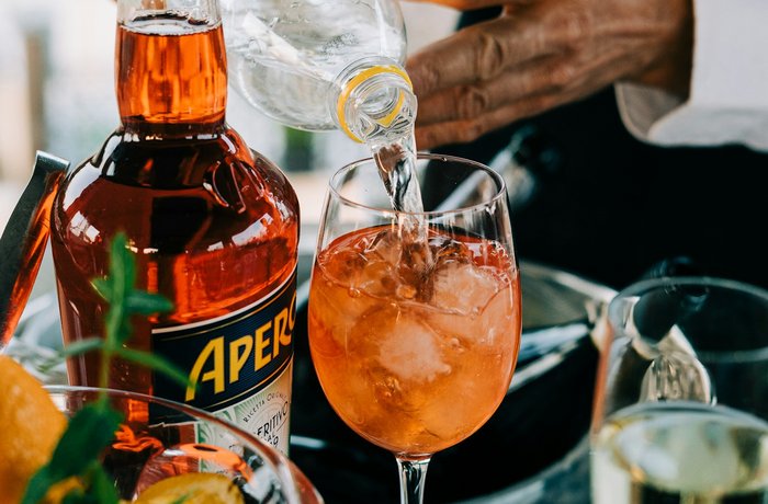 Aperol Spritz servido en vaso con botella de Aperol visible, estrategia de Campari para competir con la cerveza en eventos