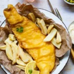 Pescado rebozado con cerveza fría, crujiente y dorado sobre papel absorbente