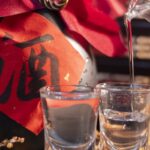 Baijiu servido en vasos junto a una botella con el carácter chino del alcohol, licor tradicional de China