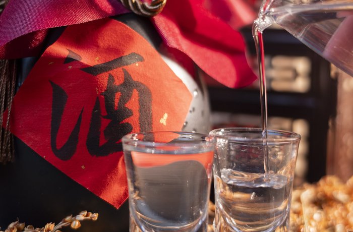Baijiu servido en vasos junto a una botella con el carácter chino del alcohol, licor tradicional de China