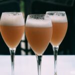Tres copas de cóctel Bellini con melocotón blanco y Prosecco sobre una mesa