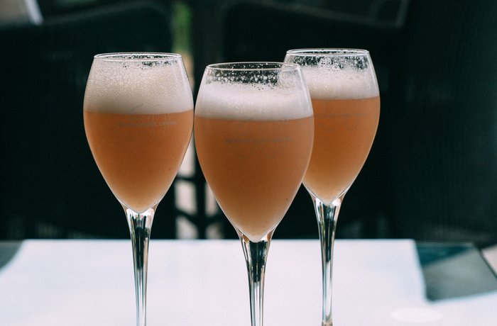Tres copas de cóctel Bellini con melocotón blanco y Prosecco sobre una mesa