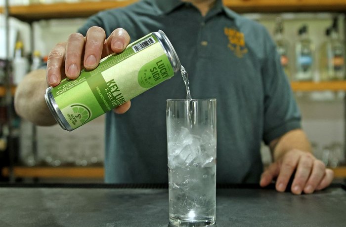 Bartender sirviendo un cóctel listo para beber Lucky Sign Spirits de lata a vaso con hielo