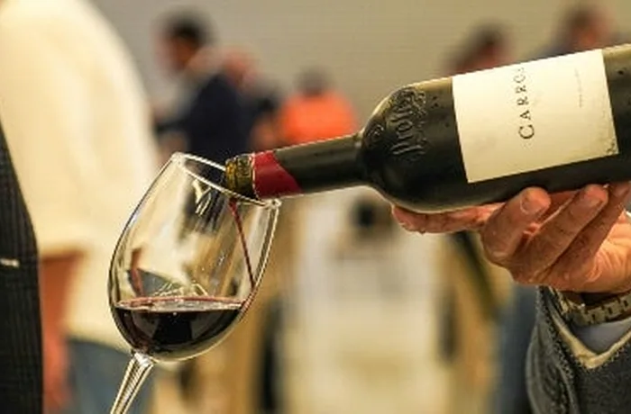 Joven consultando una aplicación de IA para elegir una botella de vino