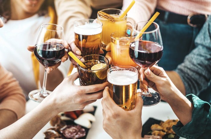 Jóvenes brindan con copas de vino, cerveza y bebidas mezcladas en México