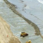 Maquinaria moviendo arena en una playa, la extracción que el proyecto de botellas de cerveza recicladas de Nueva Zelanda buscaba reducir