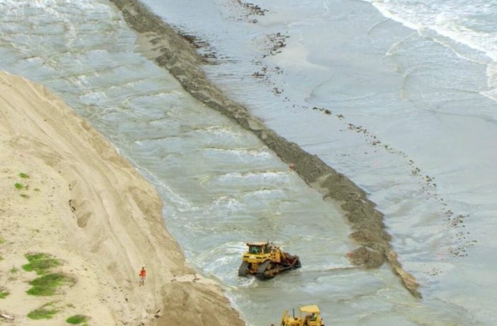 Maquinaria moviendo arena en una playa, la extracción que el proyecto de botellas de cerveza recicladas de Nueva Zelanda buscaba reducir