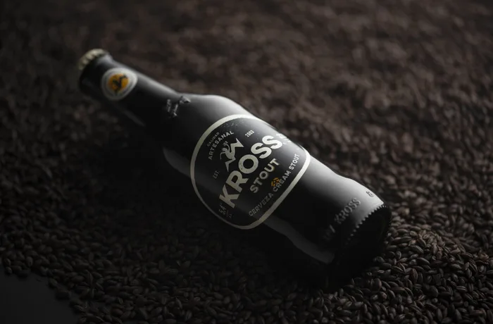 Botella de Kross Stout sobre granos de malta tostada, cerveza chilena medalla de oro