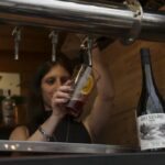 Bartender de la cervecería Wesley sirve un vermú junto a la botella de vermú Río Negro en Bariloche a la Carta