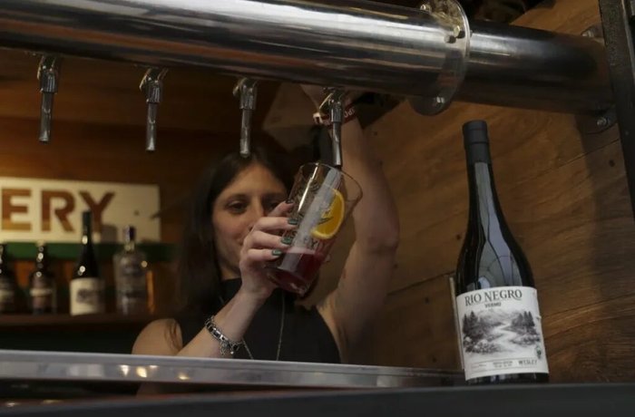 Bartender de la cervecería Wesley sirve un vermú junto a la botella de vermú Río Negro en Bariloche a la Carta